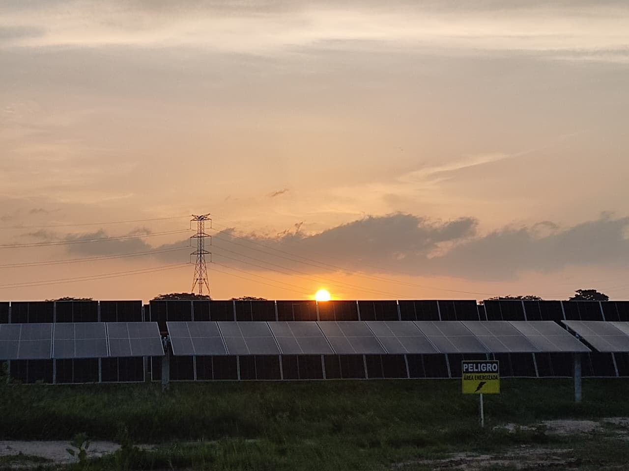 Parque solar Guayepo III al atardecer, con líneas de transmisión al fondo